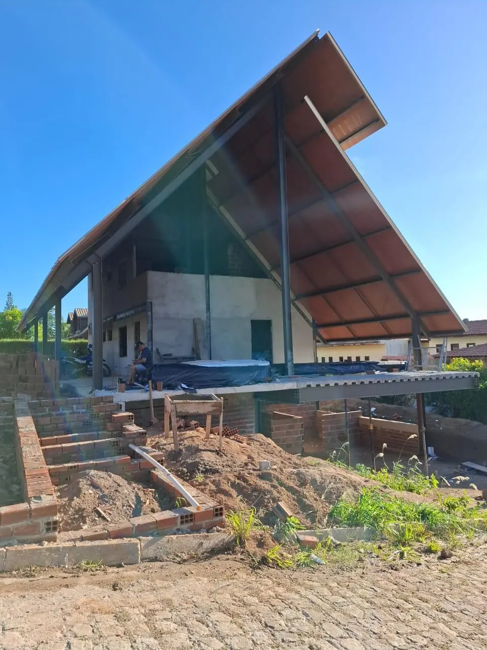 Chalé de alto padrão em construção com cobertura metálica termoacústica em balanço e estrutura metálica aparente